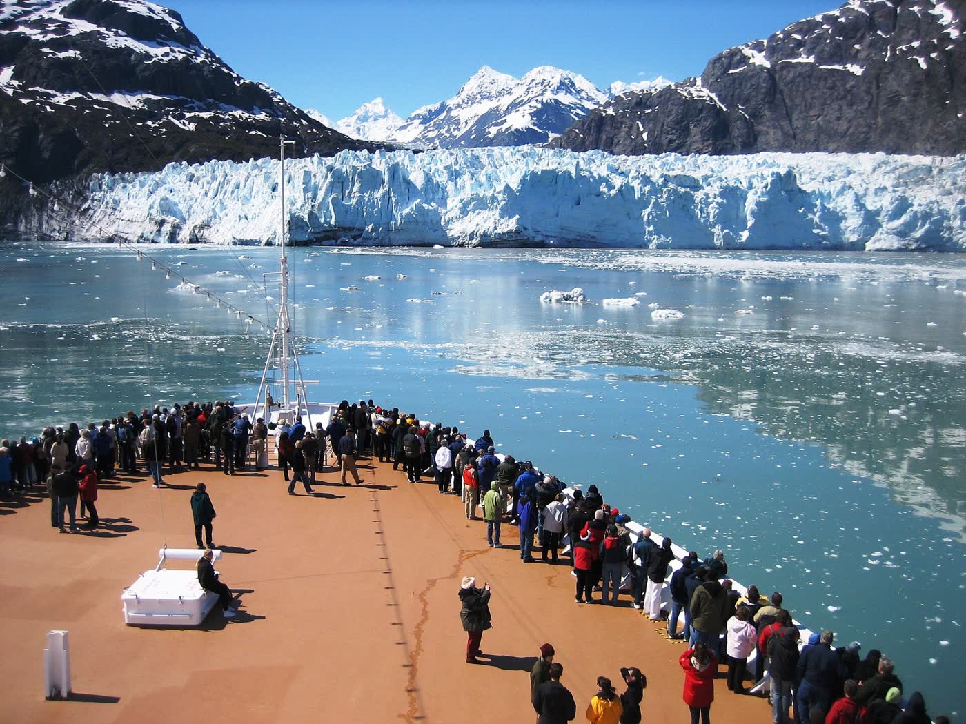 Passengers on a cruise ship's bow facing a glacier in Glacier Bay, Alaska